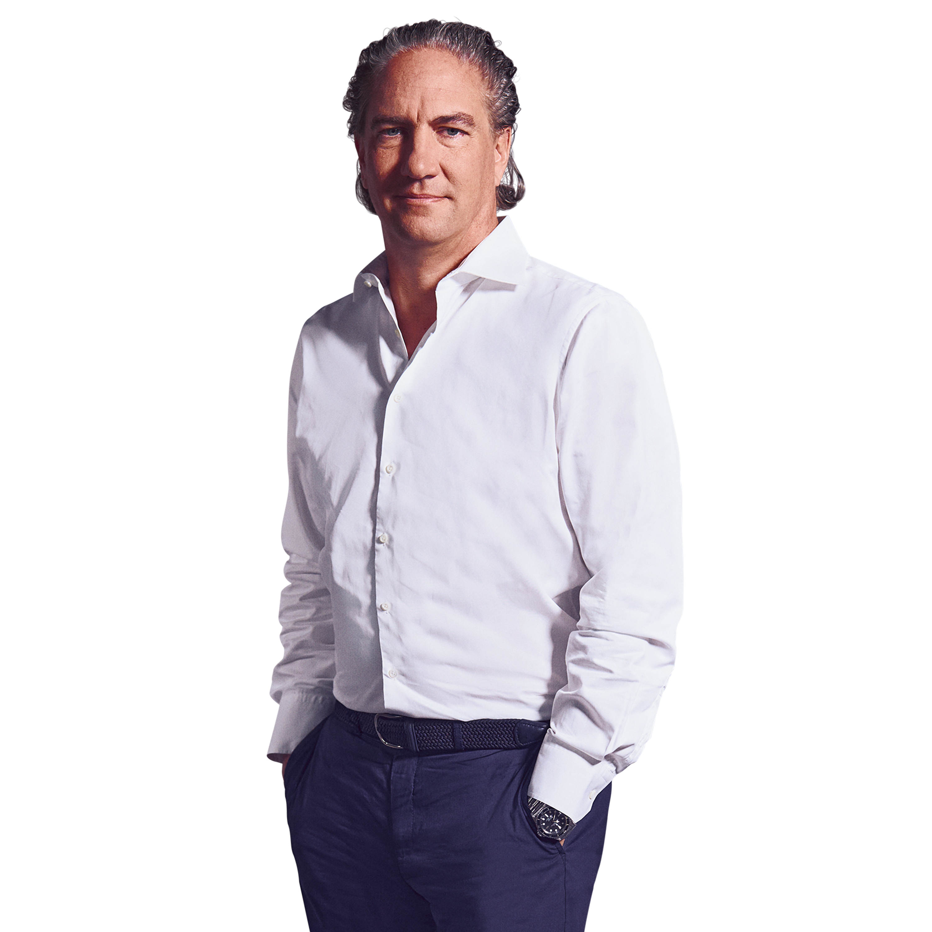 Männliche Person, graue Haare, blaue Augen, neutraler Gesichtsausdruck, trägt ein weißes Hemd, eine dunkelblaue Hose, stehend mit beiden Händen in den Hosentaschen