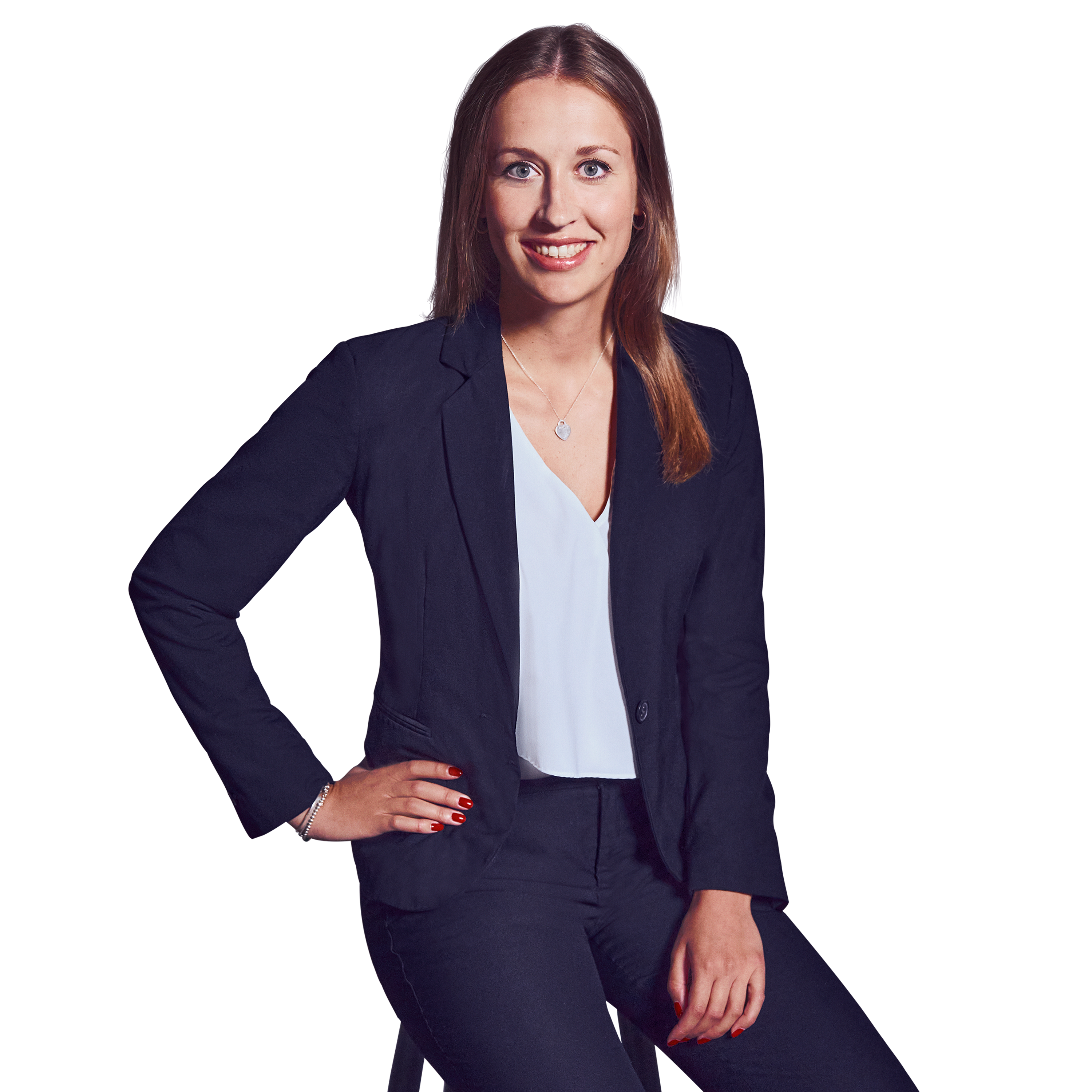 Weibliche Person, braune mittellange Haare, grüne Augen, lächelnd, trägt ein weißes Oberteil, dunkelblaue Hose und Blazer, sitzend mit der rechten Hand an der Hüfte und der linken Hand auf dem Schoß liegend