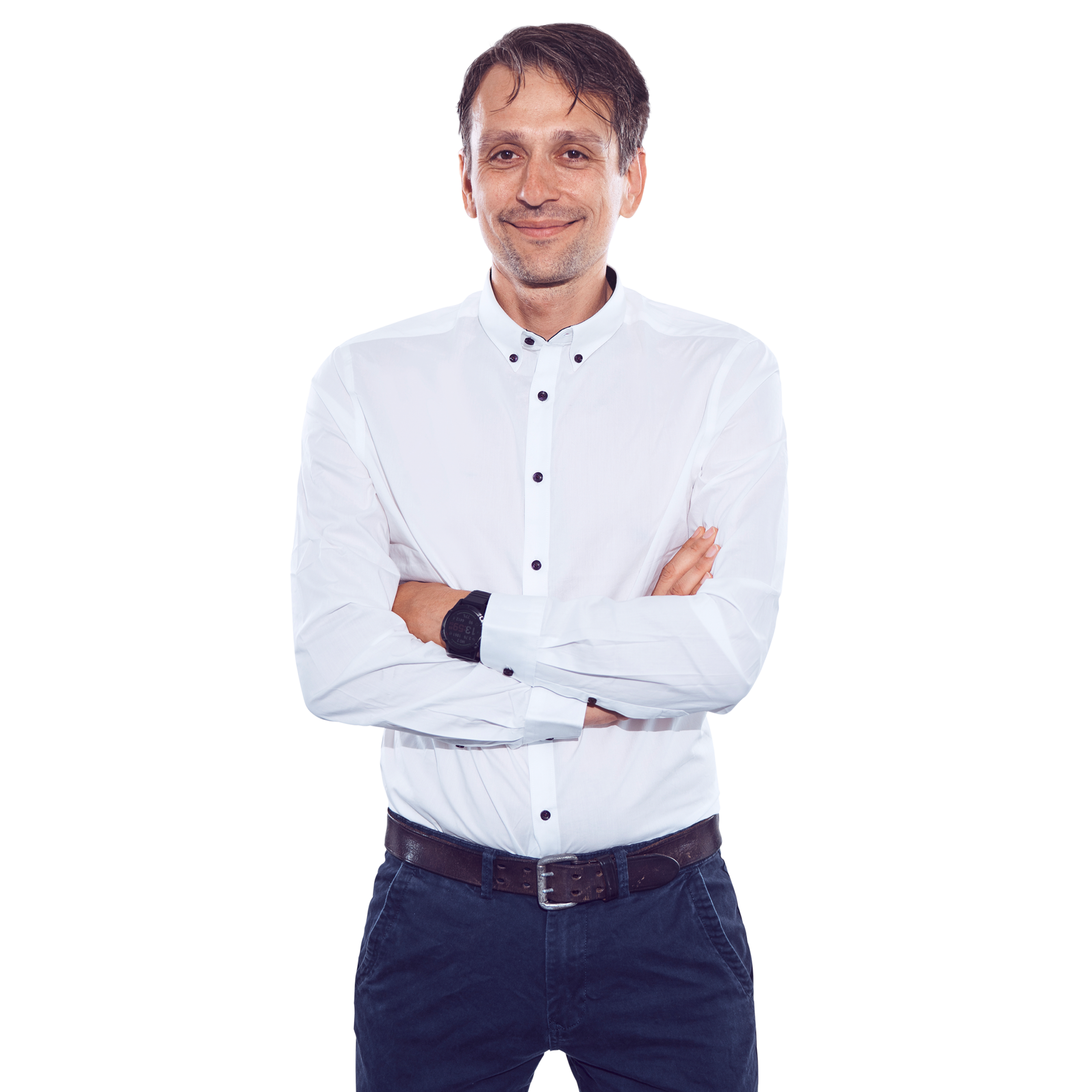 Porträtfoto von Denis Zyulyamov, Head of IT bei Kemény Boehme Consultants (KBC). Mann mit kurzen, dunkelbraunen Haaren und leichtem Bartschatten, blickt verschmitzt lächelnd in die Kamera. Trägt ein weißes Button-down-Hemd mit dunklen Knöpfen und eine dunkelblaue Chinohose mit braunem Ledergürtel sowie eine schwarze Uhr am Handgelenk. Arme verschränkt, entspannte und sympathische Haltung.