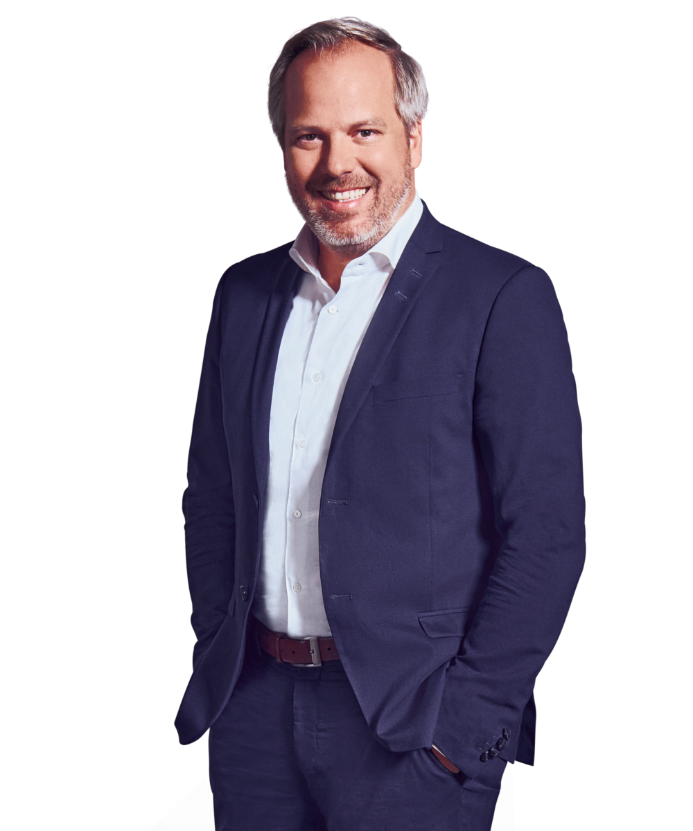 Portraitbild von Georg Huber, Senior Partner bei Kemény Boehme Consultants, der lächelnd mit beiden Händen in den Hosentaschen in die Kamera blickt