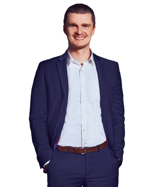 Porträtfoto von Philipp Berger, Lead Software Engineer bei Kemény Boehme Consultants (KBC). Mann mit kurzen, dunkelbraunen Haaren blickt breit lächelnd in die Kamera. Trägt einen dunkelblauen Anzug mit passendem Sakko und Hose über einem weißen Hemd ohne Krawatte sowie einen cognacfarbenen Ledergürtel, beide Hände in den Hosentaschen, lockere und offene Haltung.