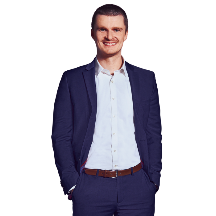 Portrait photo of Philipp Berger, Lead Software Engineer at Kemény Boehme Consultants (KBC). A man with short, dark brown hair is smiling broadly at the camera. He is wearing a dark blue suit with a matching jacket and pants over a white shirt (no tie), as well as a cognac-colored leather belt; both hands are in his pockets, and he has a relaxed and open posture.