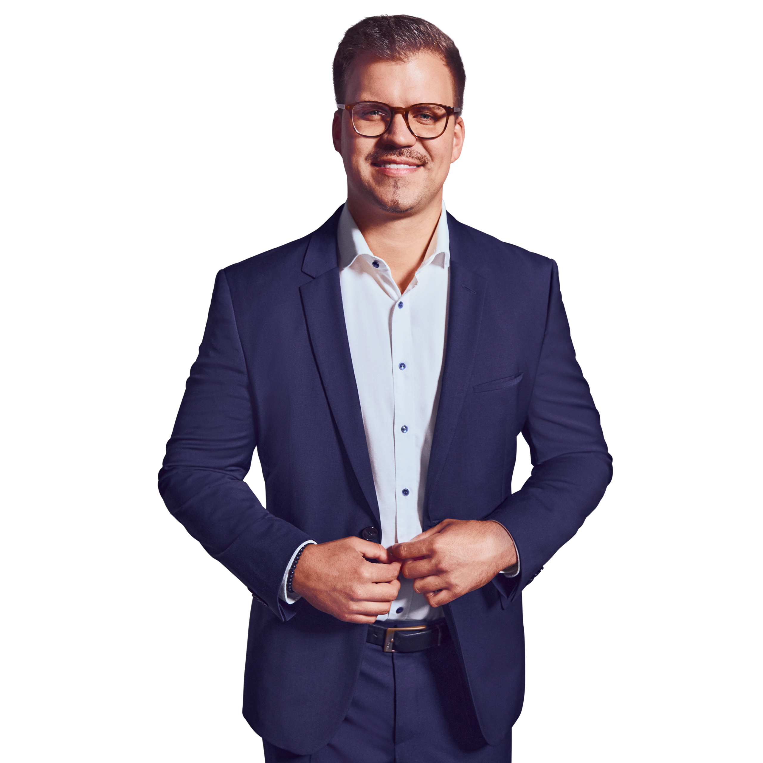 Porträtfoto von Markus Stingl, Manager bei Kemény Boehme Consultants (KBC). Mann mit kurzen, dunkelbraunen Haaren, einem gepflegten Kinnbärtchen und einer markanten braungemusterten Hornbrille blickt freundlich lächelnd in die Kamera. Trägt einen dunkelblauen Anzug mit passendem Sakko und Hose über einem weißen Hemd mit blauen Knöpfen ohne Krawatte sowie einen schwarzen Ledergürtel, beide Hände locker vor dem Körper verschränkt, offene und sympathische Haltung.