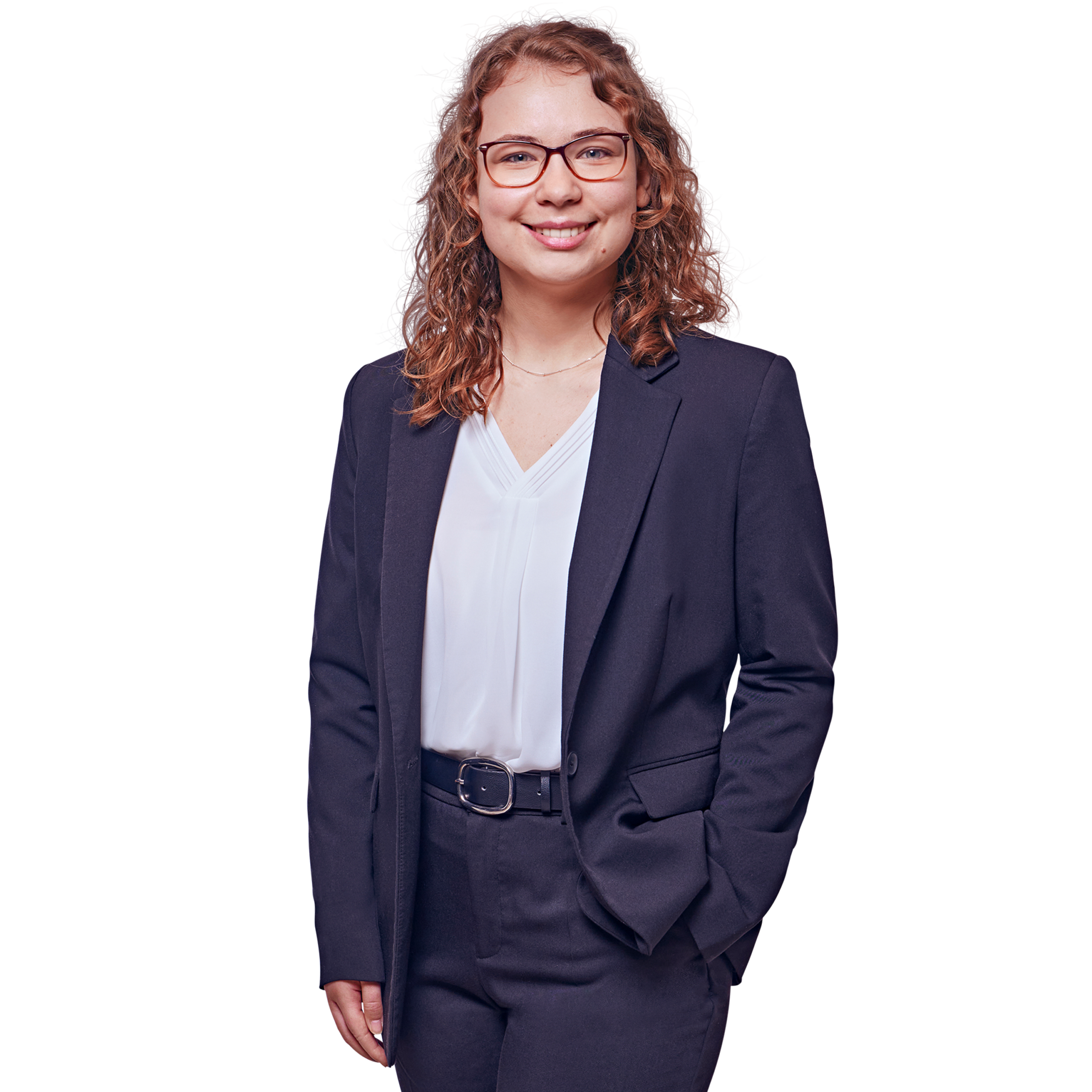 Porträtfoto von Sophie-Theres Altmann, Consultant bei Kemény Boehme Consultants (KBC). Frau mit schulterlagen, lockigen rotbraunen Haaren und einer markanten eckigen Brille mit rotem Rahmen, blickt freundlich lächelnd in die Kamera. Trägt ein dunkelblaues Sakko über einer weißen V-Ausschnitt-Bluse und eine dunkle Hose mit schwarzem Gürtel sowie eine feine Halskette. Eine Hand in der Hosentasche, entspannte und professionelle Haltung.