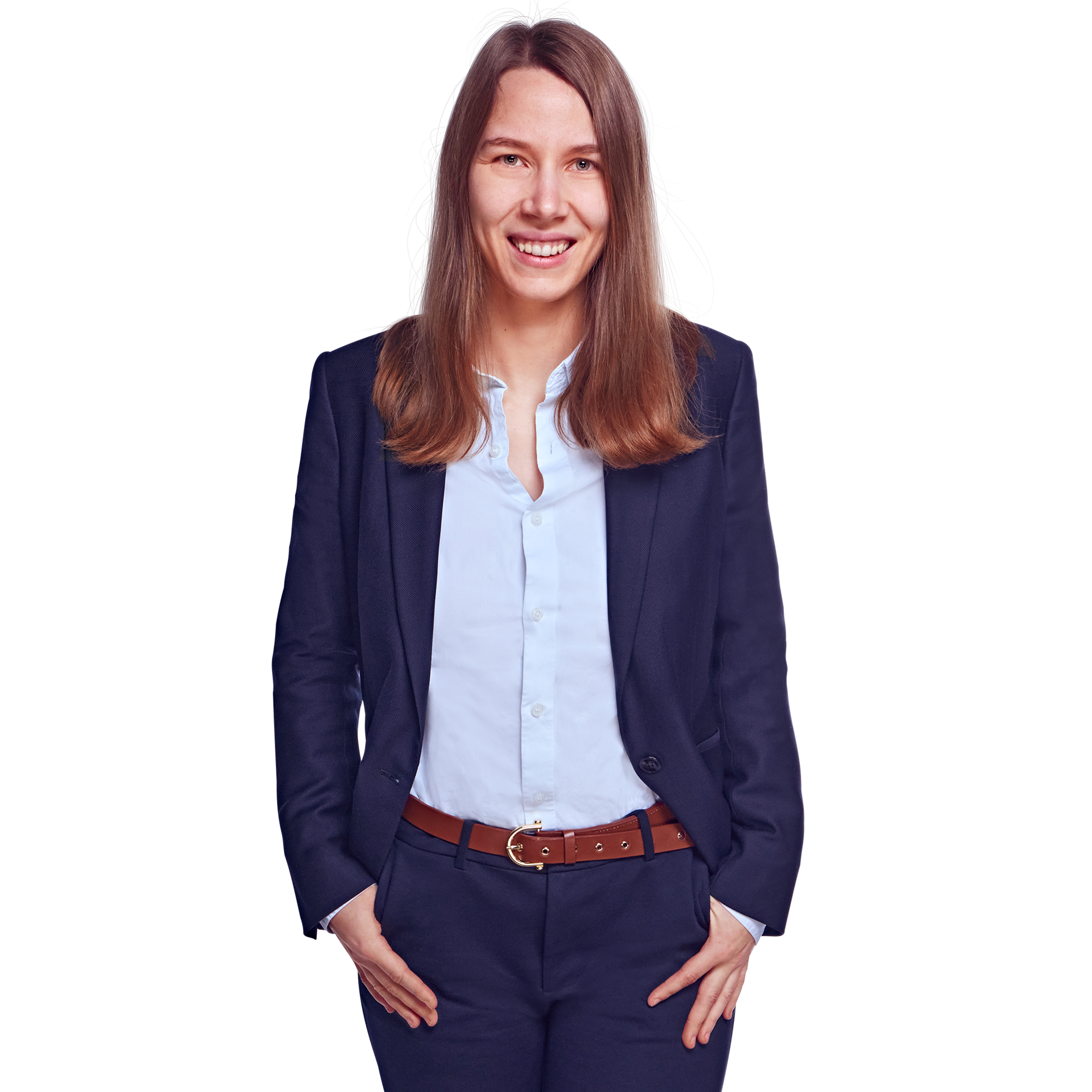 Weibliche Person, braune mittellange Haare, grüne Augen, lächelnd, trägt eine weiße Bluse, dunkelblaue Hose und Blazer, stehend mit beiden Händen in den Hosentaschen