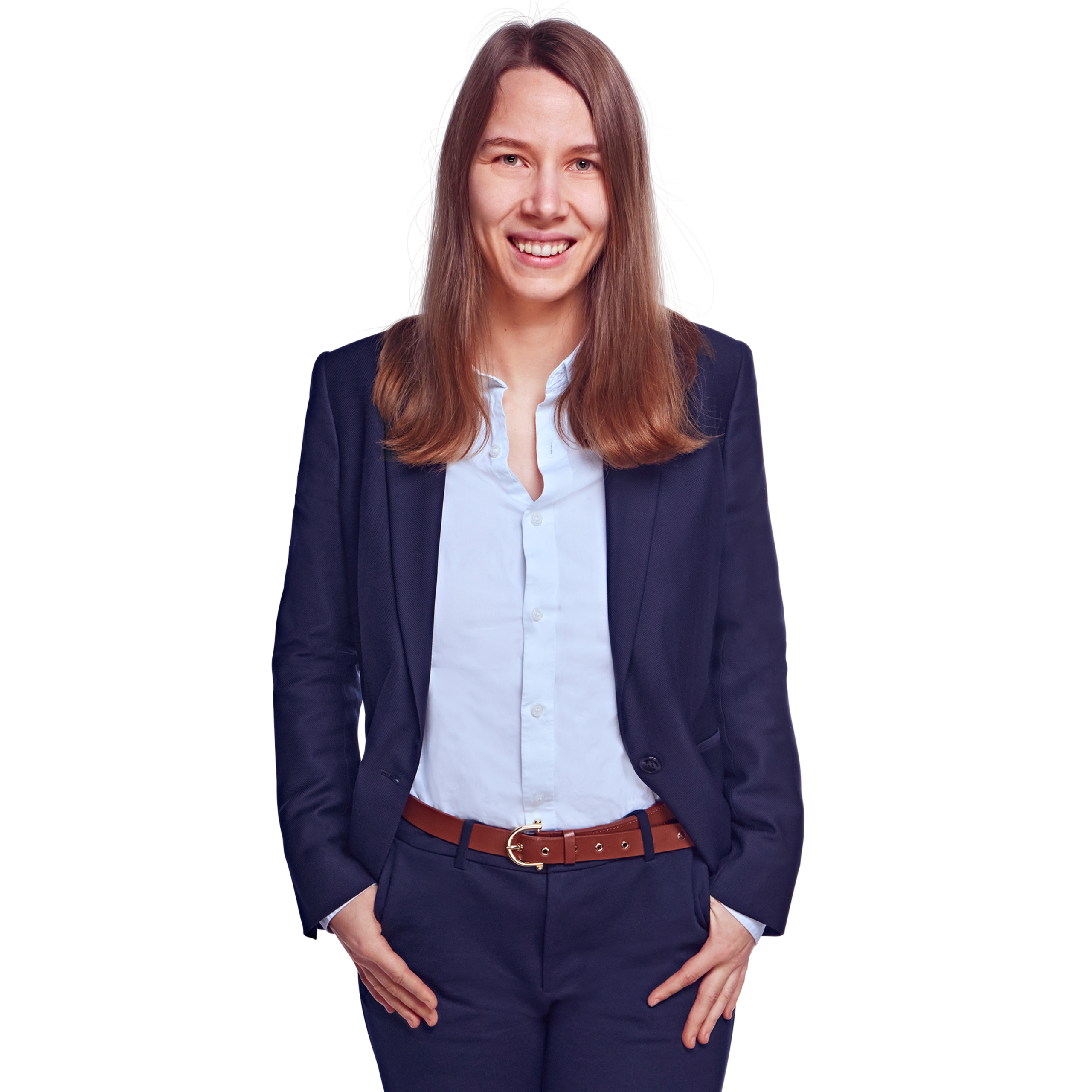 Porträtfoto von Luisa Ehmcke, Senior Consultant bei Kemény Boehme Consultants (KBC). Frau mit langem, glattem, dunkelbraunem Haar blickt breit lächelnd in die Kamera. Trägt einen dunklen Blazer über einer hellblauen, offen getragenen Bluse sowie eine markante cognacfarbene Ledergürtel mit goldener Schnalle und dunkle Hose, beide Hände locker in den Hosentaschen, aufrechte und offene Haltung.