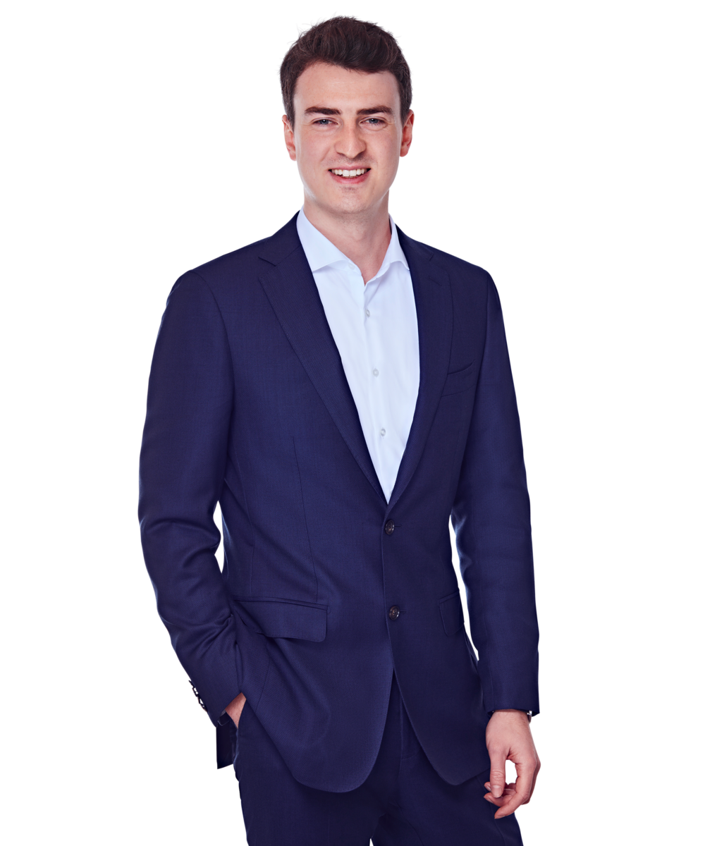 Porträtfoto von Oliver Siebe, Senior Consultant bei Kemény Boehme Consultants (KBC). Mann mit kurzem, dunkelbraunem, leicht gewelltem Haar blickt breit lächelnd in die Kamera. Trägt einen dunkelblauen Zweiknopf-Blazer über einem hellblauen Hemd ohne Krawatte, offen getragen, eine Hand locker in der Hosentasche, die andere seitlich am Körper, leicht zur Seite gedrehte, entspannte und selbstbewusste Haltung.