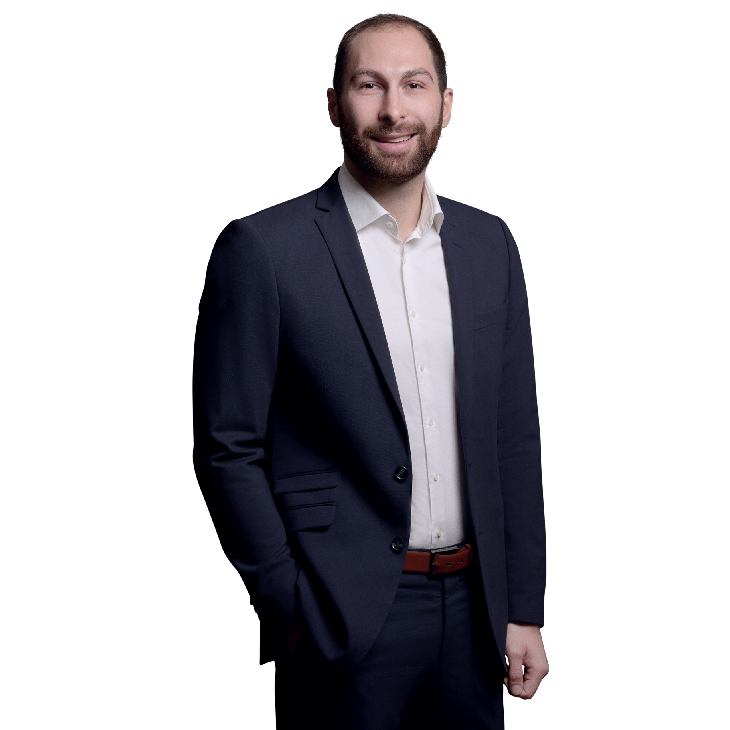 orträtfoto von Dominik Langer, Senior Consultant bei Kemény Boehme Consultants (KBC). Mann mit kurzen dunkelbraunen Haaren und Dreitagebart, blickt freundlich lächelnd in die Kamera. Trägt ein dunkelblaues Sakko über einem weißen Hemd ohne Krawatte, entspannte Haltung mit einer Hand in der Hosentasche.