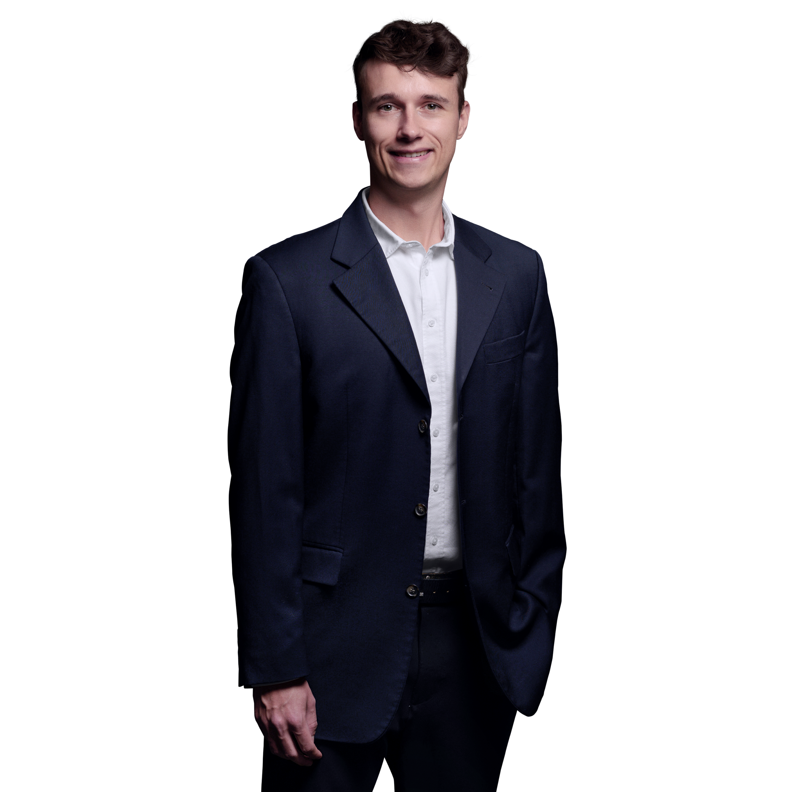 Porträtfoto von Julian Otto, Consultant bei Kemény Boehme Consultants (KBC). Mann mit lockigen dunkelbraunen Haaren, blickt freundlich lächelnd in die Kamera. Trägt ein dunkelblaues Sakko über einem weißen Hemd ohne Krawatte, entspannte Haltung mit einer Hand in der Hosentasche.