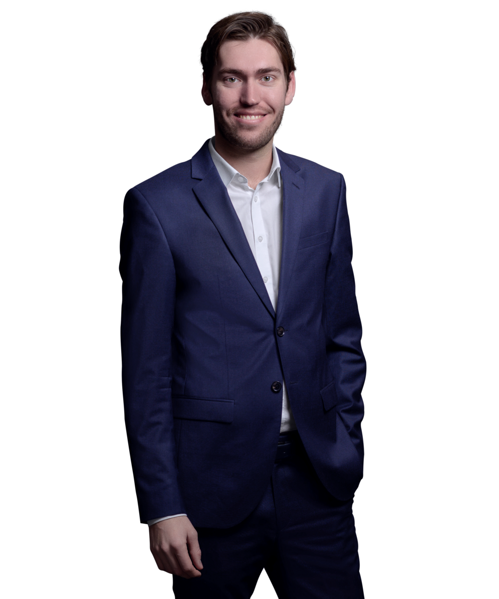 Porträtfoto von Maximilian Hein, Consultant bei Kemény Boehme Consultants (KBC). Mann mit lockigen dunkelbraunen Haaren und kurzem Bart, blickt breit lächelnd und offen in die Kamera. Trägt ein dunkelblaues Sakko über einem weißen Hemd ohne Krawatte, Arme selbstbewusst vor der Brust verschränkt.