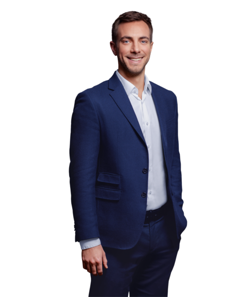 Portrait photo of Johannes Stiegeler, a manager at Kemény Boehme Consultants (KBC). A man with short dark brown hair and blue eyes, smiling warmly at the camera. He is wearing a navy blue jacket over a light blue shirt.